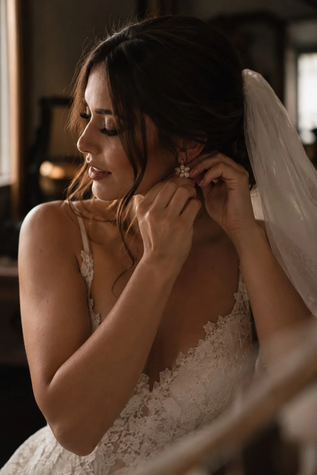 A bride fastening her earring by the window
